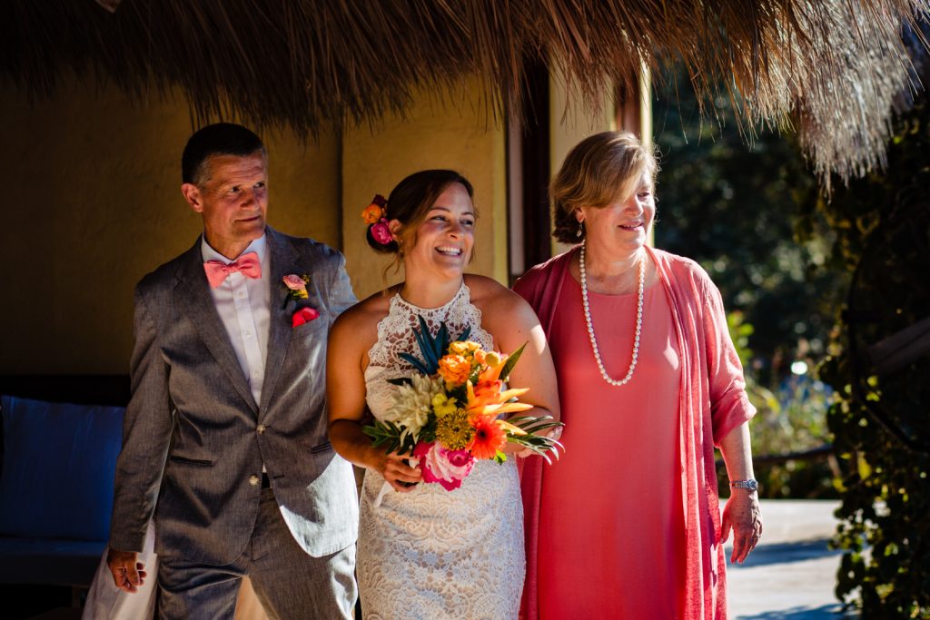 the bride with her mum and dad walking to the altar 