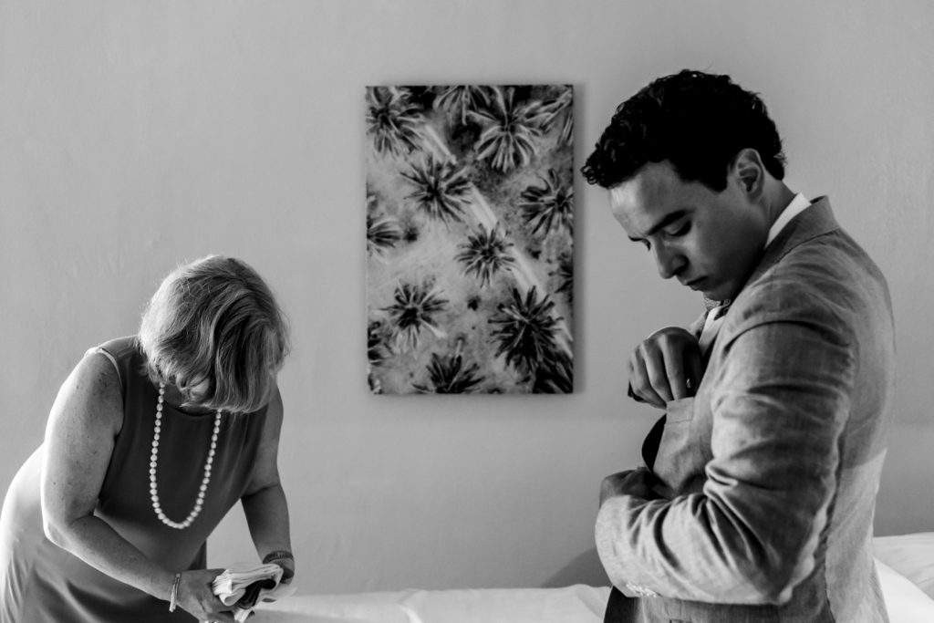 groom gettin ready in the room fixing his suit  with his mum in the room