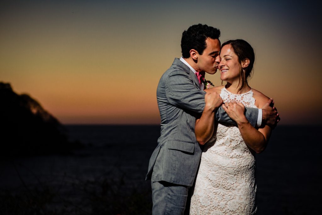 bride and groom hugs at the sunset  the groom kiss her and the bride smile