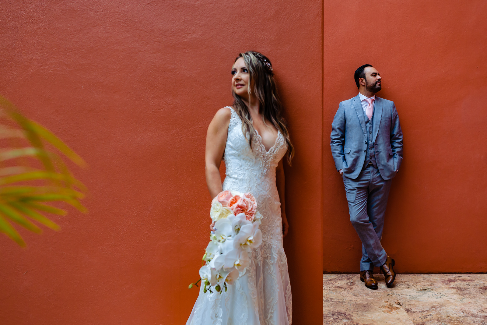 bride and groom on a red wall