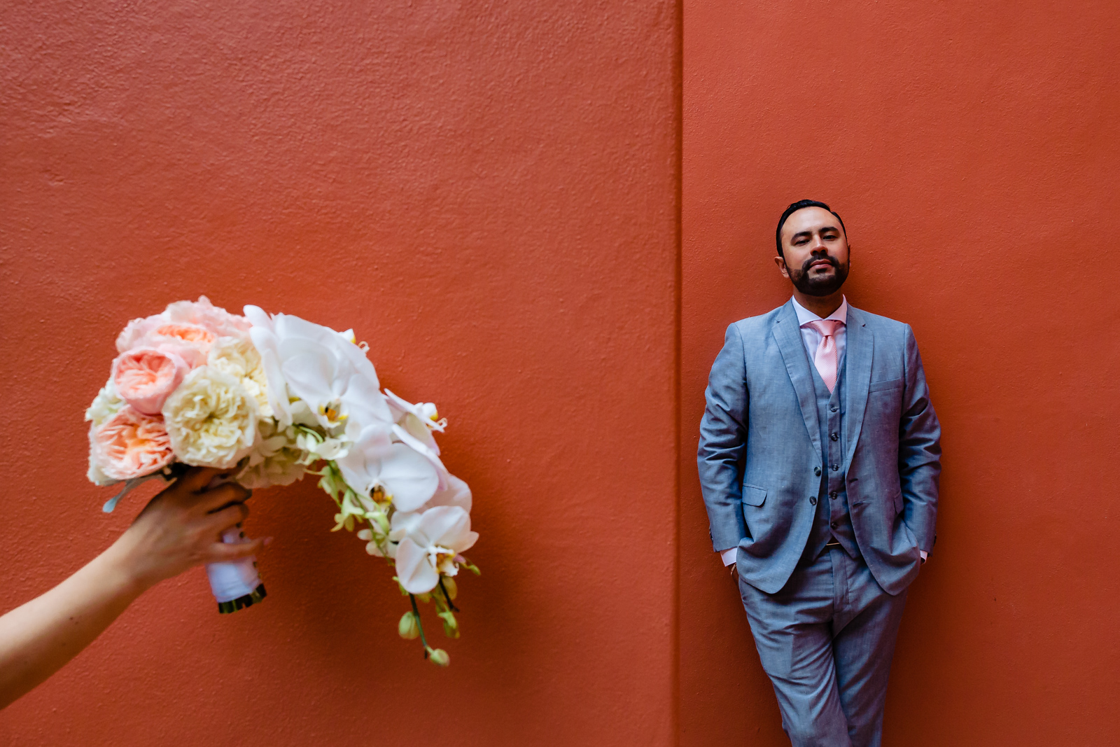 flowers and groom on a red wall