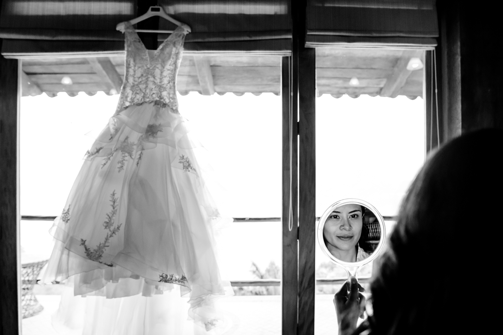 bride look in the mirror with the dress hang on the windows 