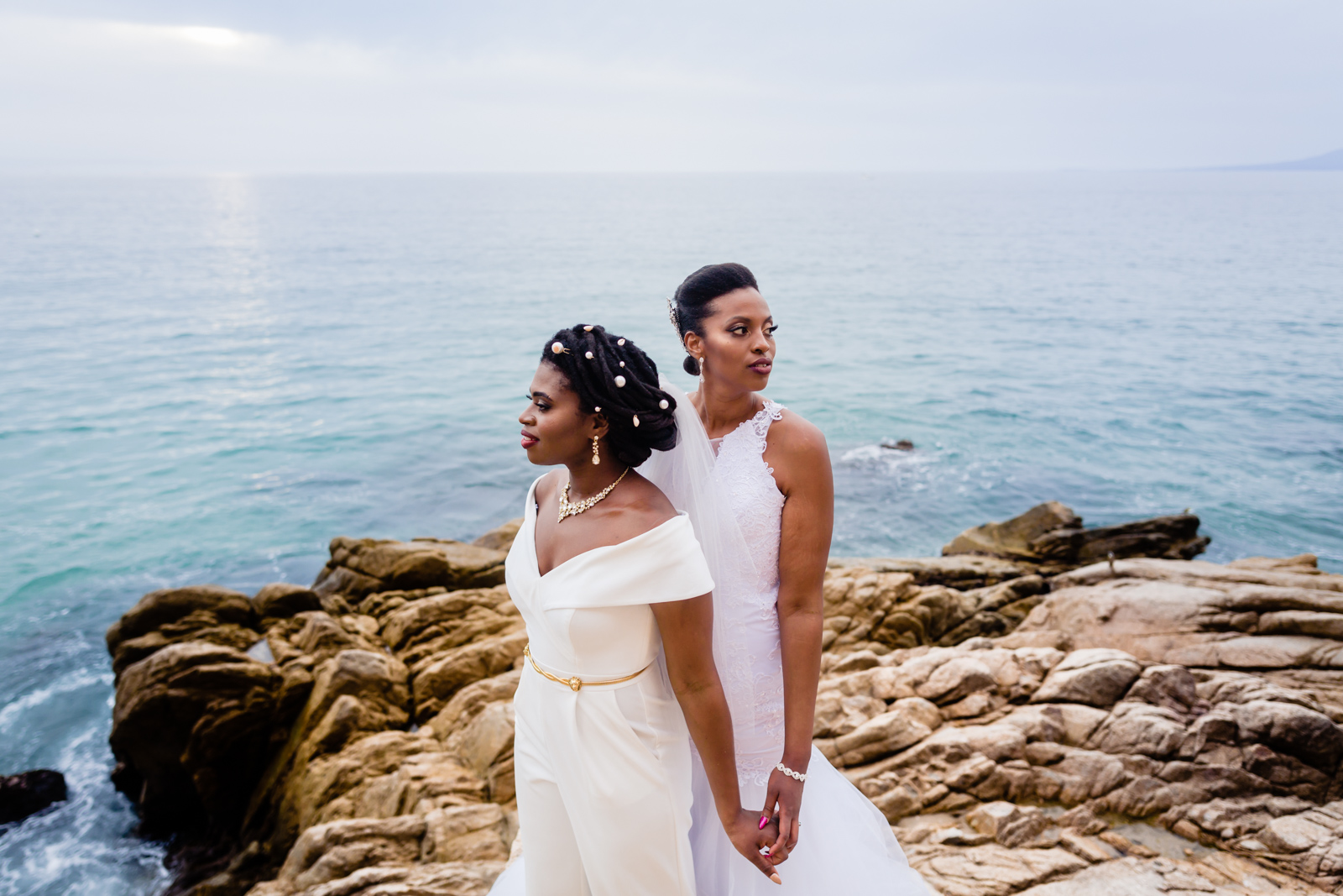 brides holding hands with ocean o the background during the sunset time