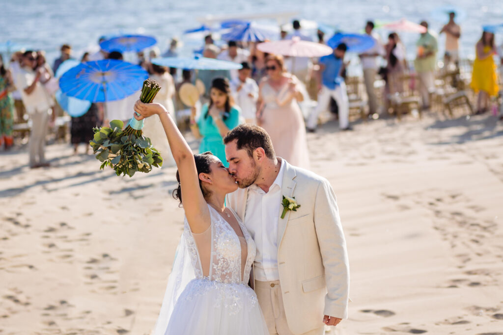 bride and groom kissing each other with the ceremony on the background the bride is holding the bouquet 