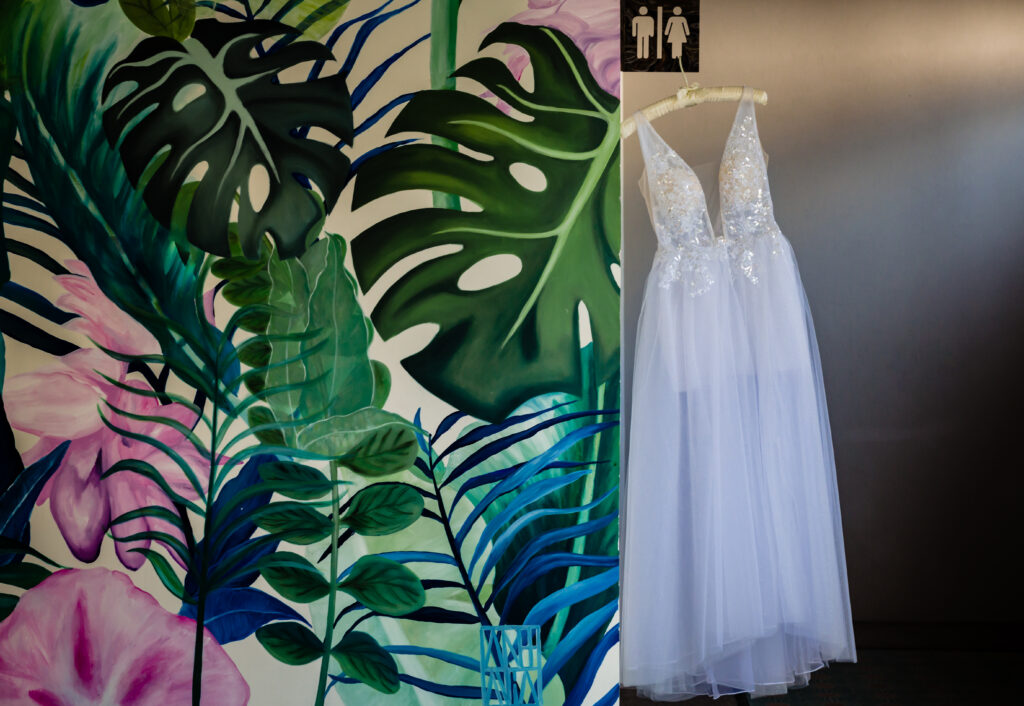 wedding dress hang on a toilet sign with a wall with flowers painted on it at the Hilton resort Puerto Vallarta 